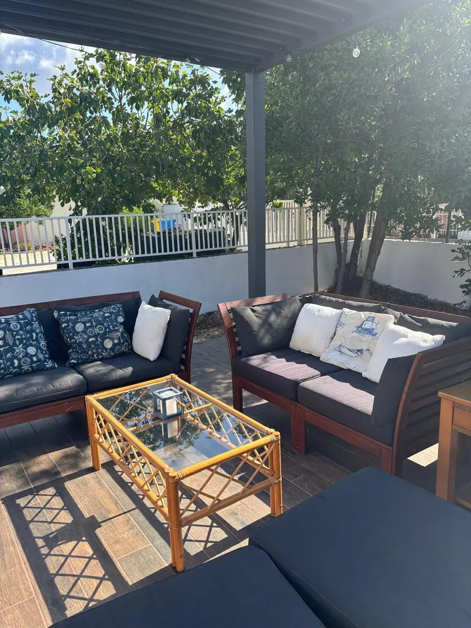 Two sofas with blue and white cushions around a glass-topped rattan table on the terrace