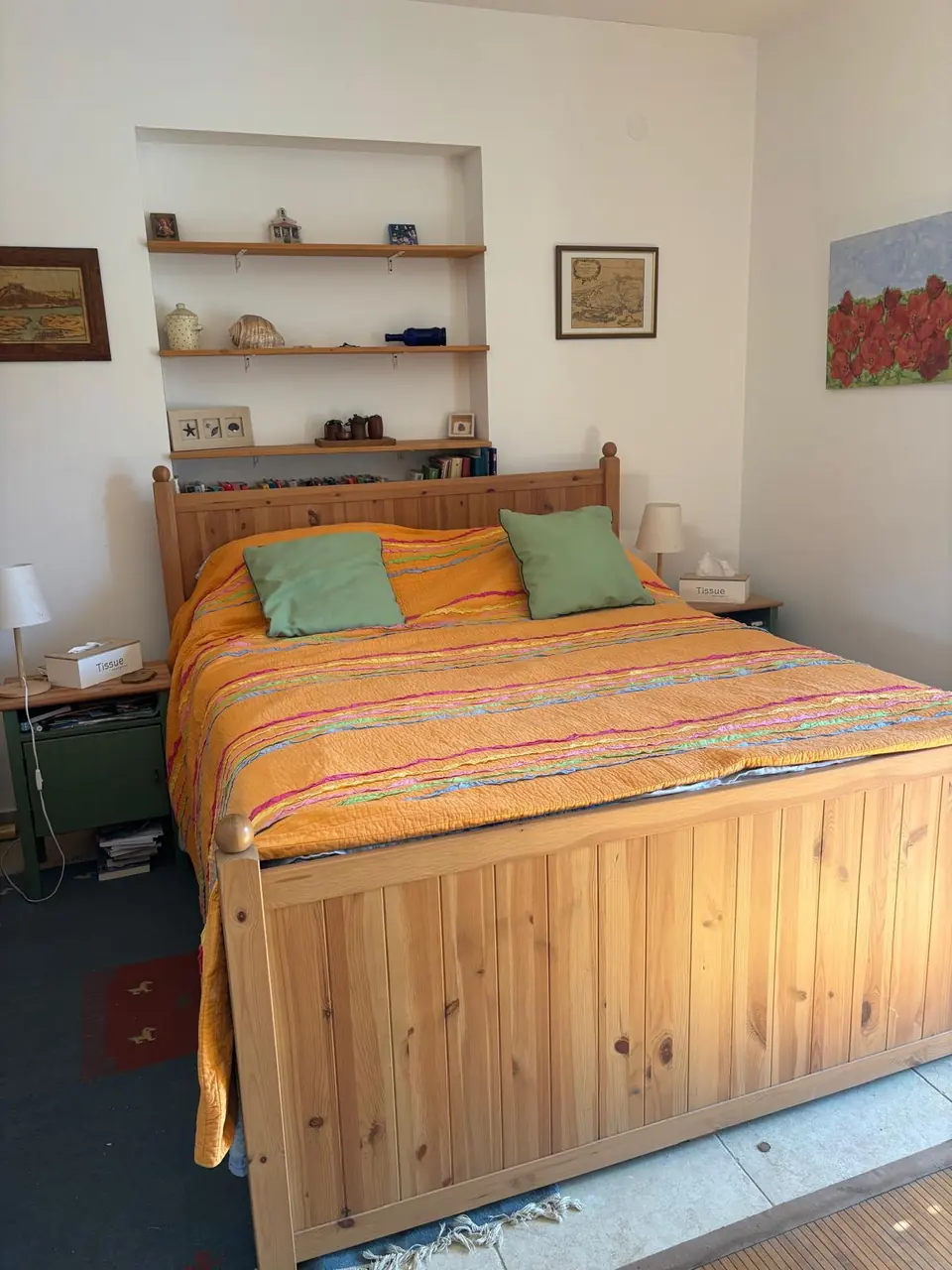 Bedroom with a pine double bed, orange quilt and shelves in an alcove