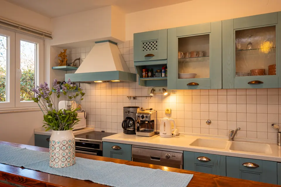 Kitchen with pale green cabinets, a coffee machine and a long worktop