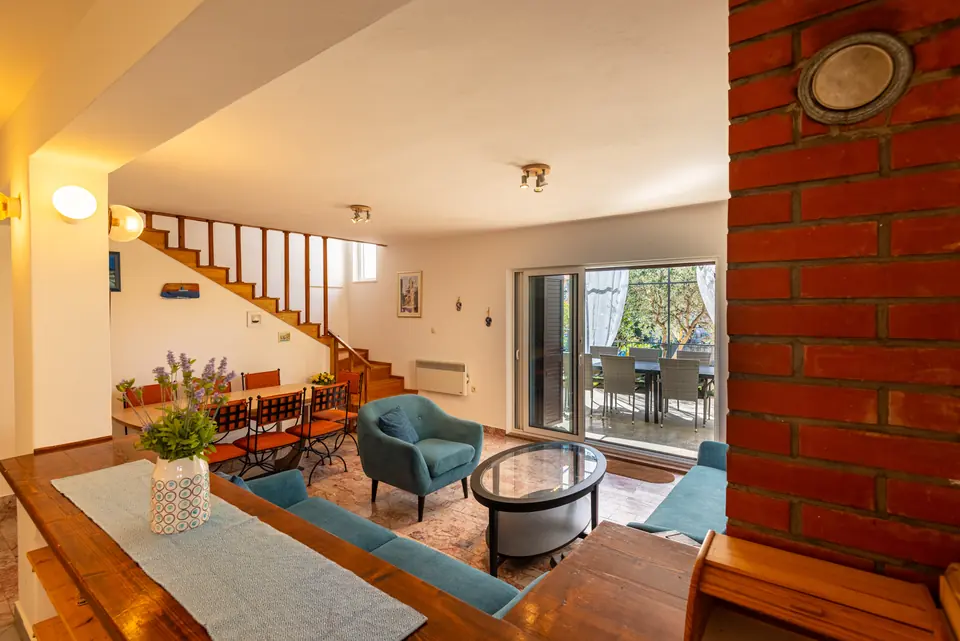 Living room with blue armchairs and a brick pillar, opening onto the terrace