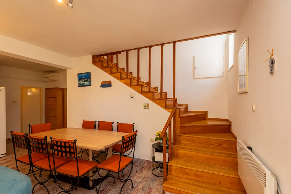 Indoor dining table with orange chairs beside the wooden staircase