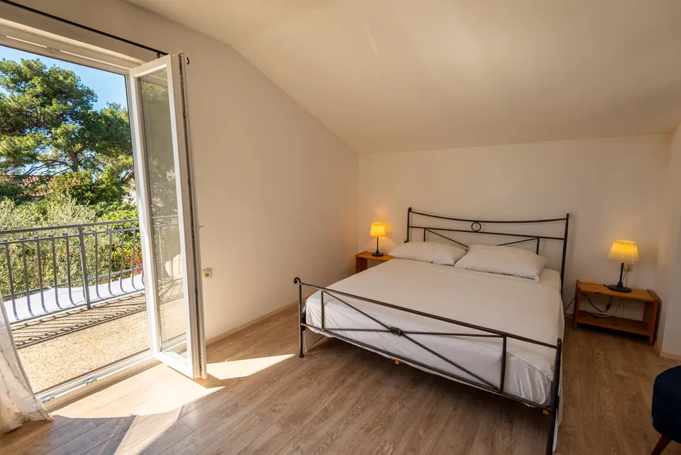 Bedroom with an iron bedstead and balcony doors open onto the garden