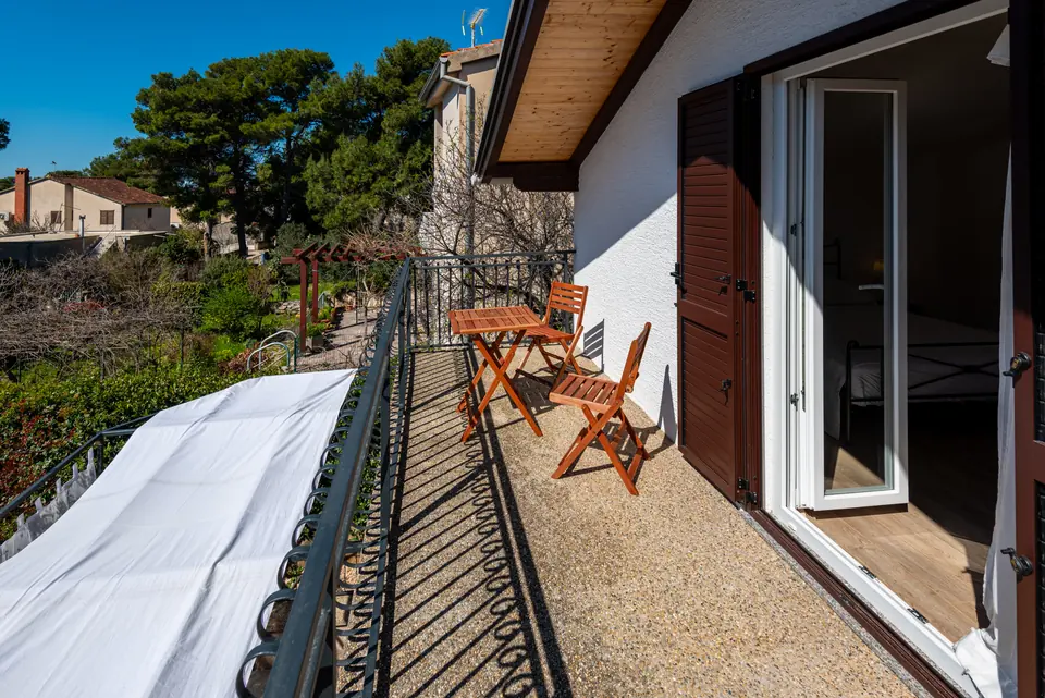 Upstairs balcony with a bistro table and chairs, looking into the pines